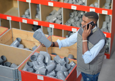 man on telephone holding plumbing fittings