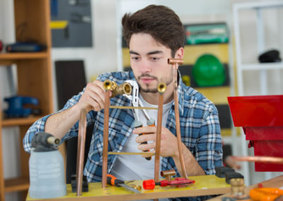 Young plumber fixing copper pipe