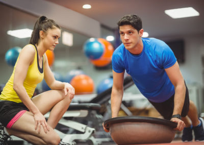 Fit woman working out with trainer at the gym