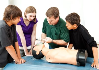 Teacher demonstrates to students how to use an oxygen mask for cpr.