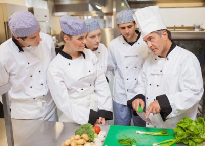 Trainees learning vegetable slicing in the kitchen