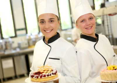 Students girls in pastry holding cakes