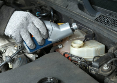 Auto mechanic topping up brake fluid in the vehicle