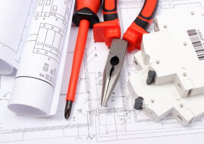 Rolled electrical diagrams, electric fuse and work tools lying on construction drawing of house, drawings for the projects engineer jobs