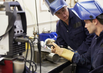 Engineer teaching apprentice to use tig welding machine