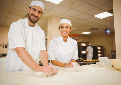 Team of bakers kneading dough in a commercial kitchen