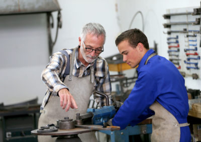 Young man in ironworks training with professional teacher