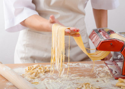 Young woman chef prepares homemade pasta from durum semolina flour