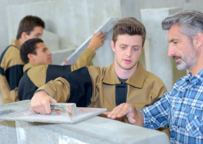 Teacher showing apprentice how to float cement