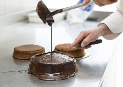 Pastry chef covering cake with melted chocolate