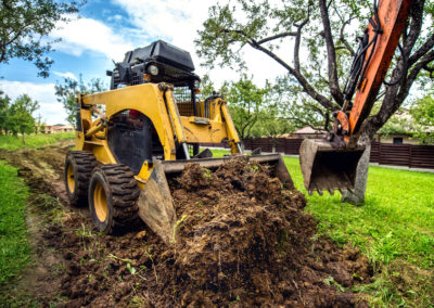 Yellow mini bulldozer working with earth, moving soil and doing landscaping works