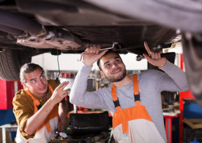 Two car mechanics at workshop at work.