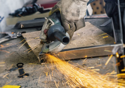 Welder with construction gloves grinding metal at an angle